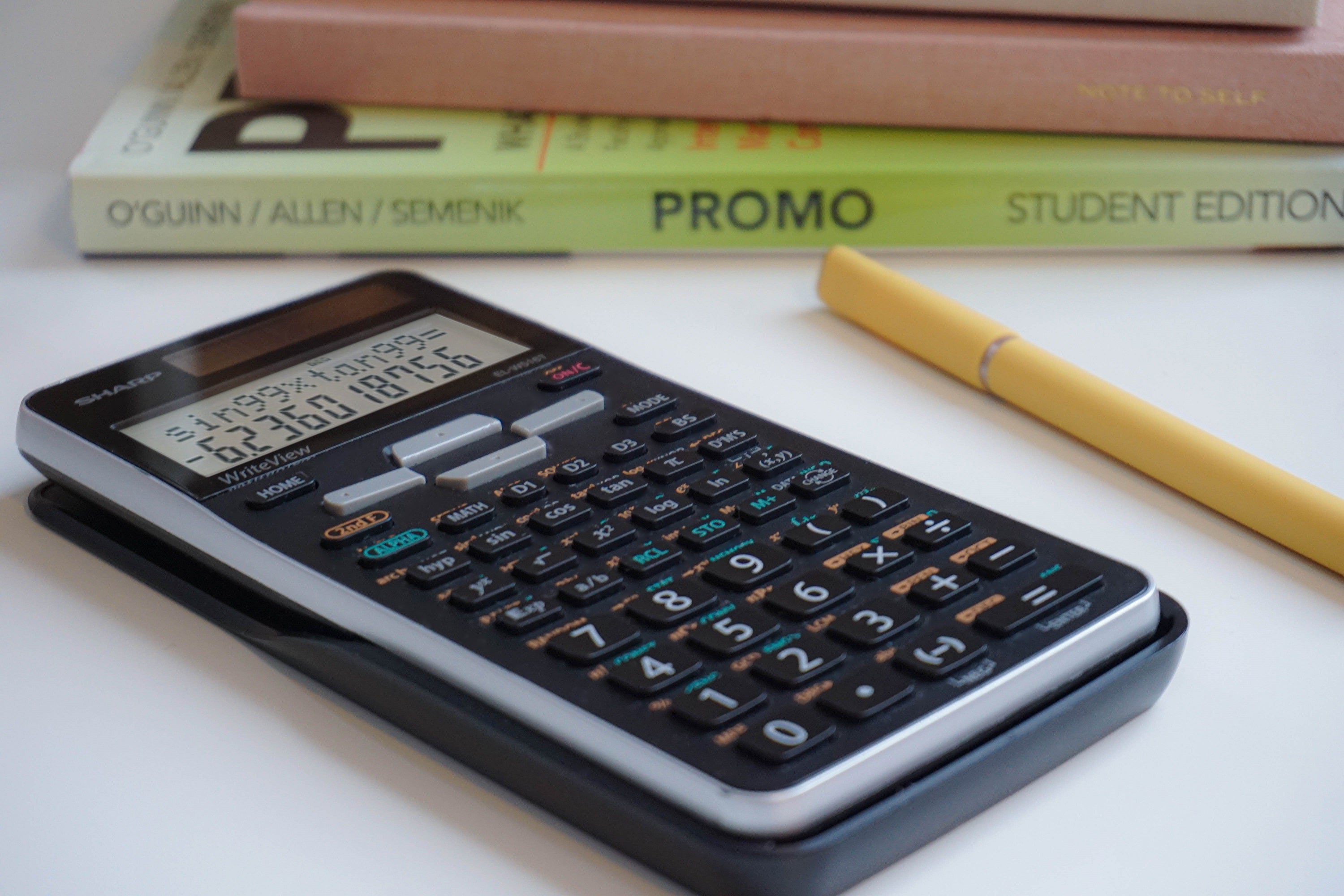 black scientific calculator with math textbooks in the background